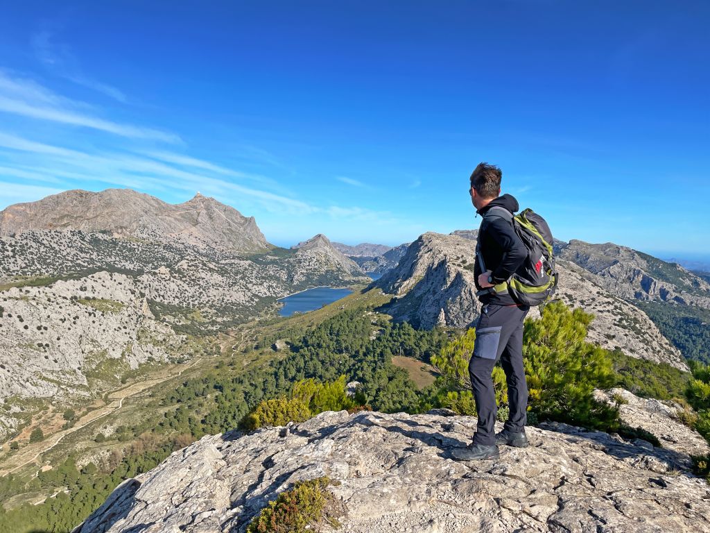 Escursionista su una collina verdeggiante con vista sul mare, trekking con "Girolibero" a Maiorca