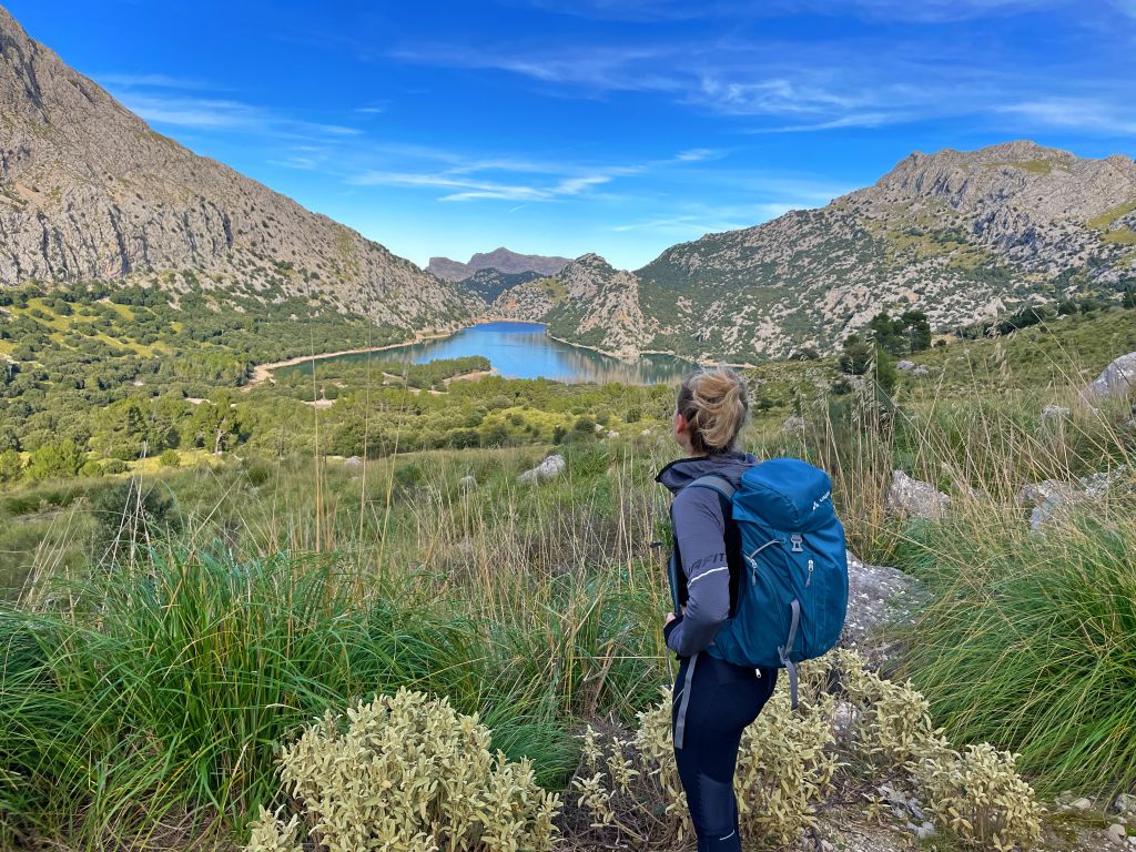 Escursionista in montagna, circondato da natura e con vista sulle colline di Maiorca