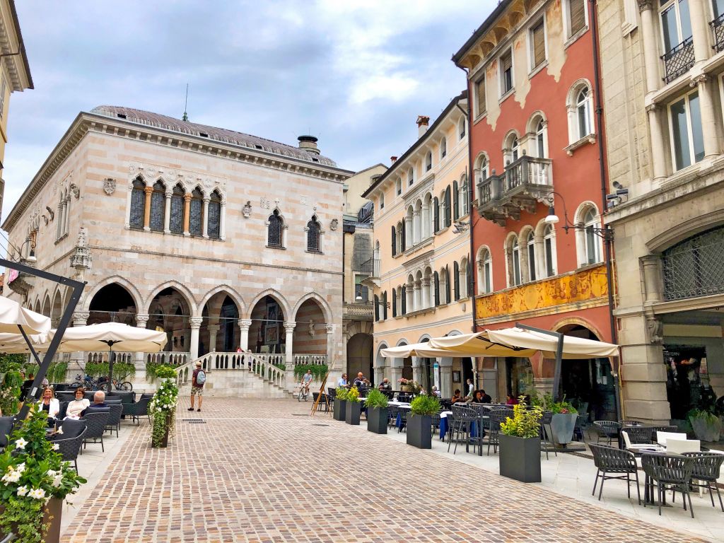 Piazza con caffè all’aperto e negozi nel centro storico di Tarvisio, Italia.