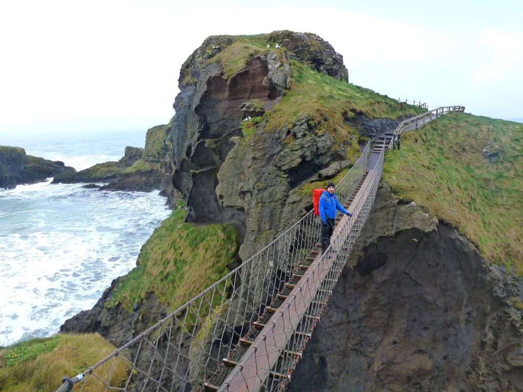 Escursionisti sul ponte di corda di Carrick-a-Rede che collega due scogliere sopra l'oceano, Irlanda del Nord.
