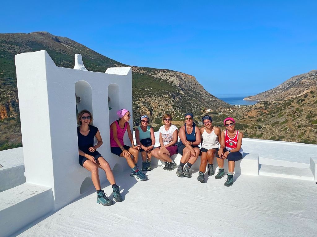 Gruppo in viaggio con "Girolibero", foto seduti vicino a edifici bianchi tradizionali, trekking in Grecia