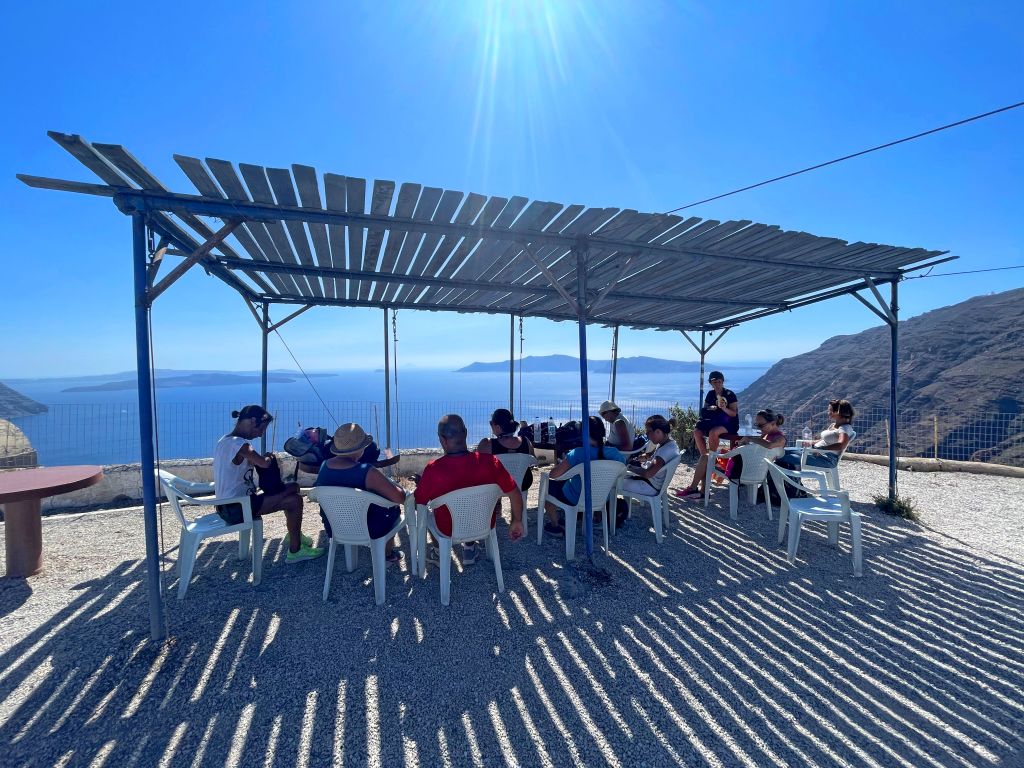 Gruppo seduto sotto una pergola ombreggiata durante una sosta lungo un trekking sull'isola di Sifnos.