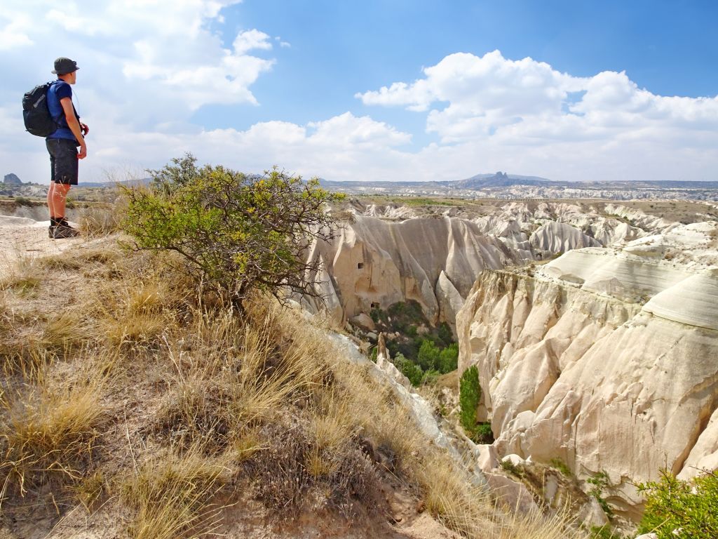 Escursionista su una collina che osserva la valle rocciosa in Cappadocia.