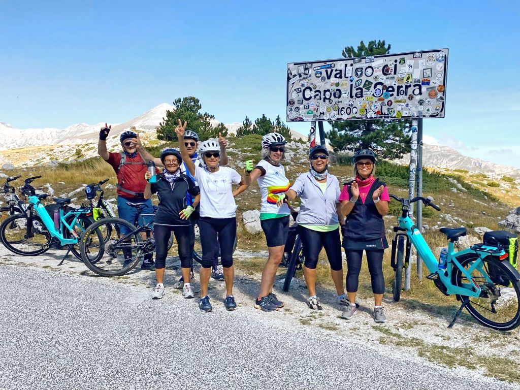 Gruppo di ciclisti in posa davanti al cartello "Campo Imperatore", Abruzzo, Italia