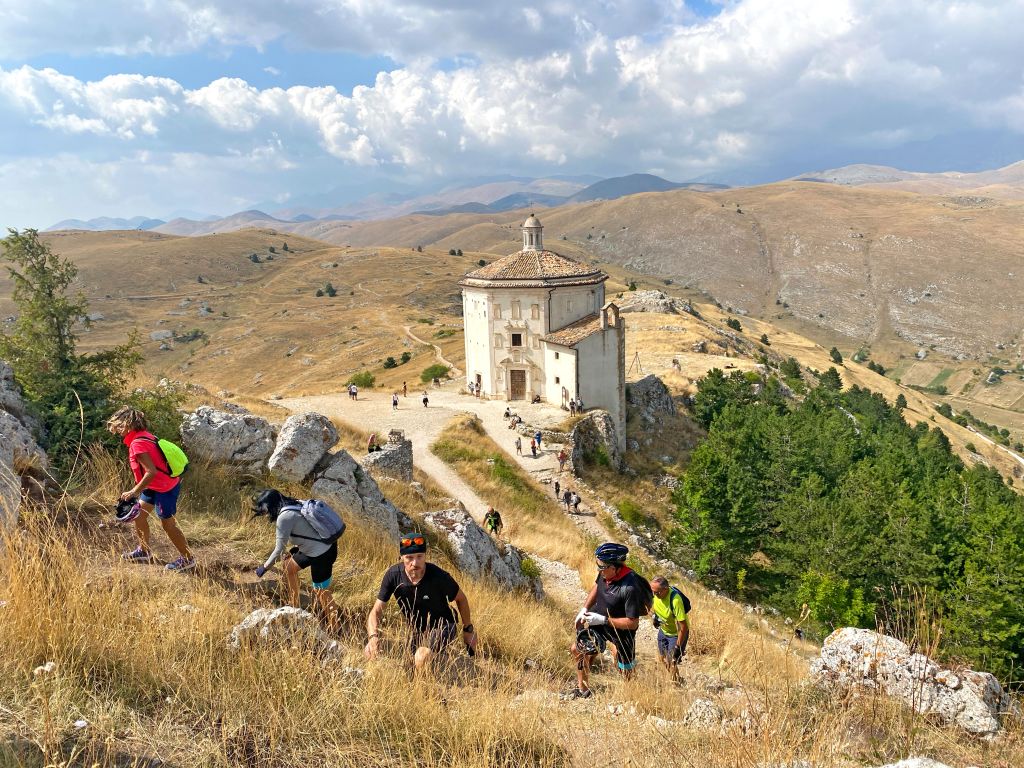 Escursionisti su un sentiero di montagna con rovine storiche, Abruzzo, Italia
