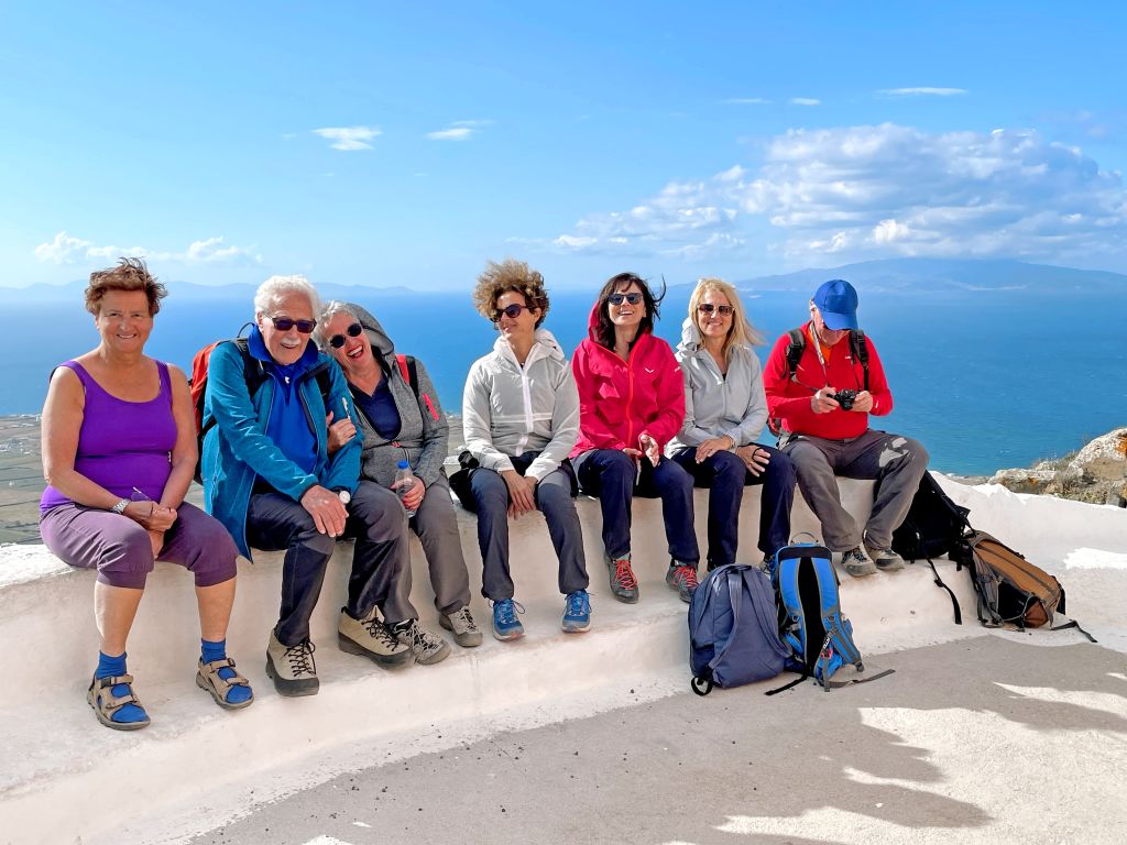 Gruppo di turisti seduti su una terrazza panoramica con vista sul mare, foto ricordo tour "Girolibero" a Santorini