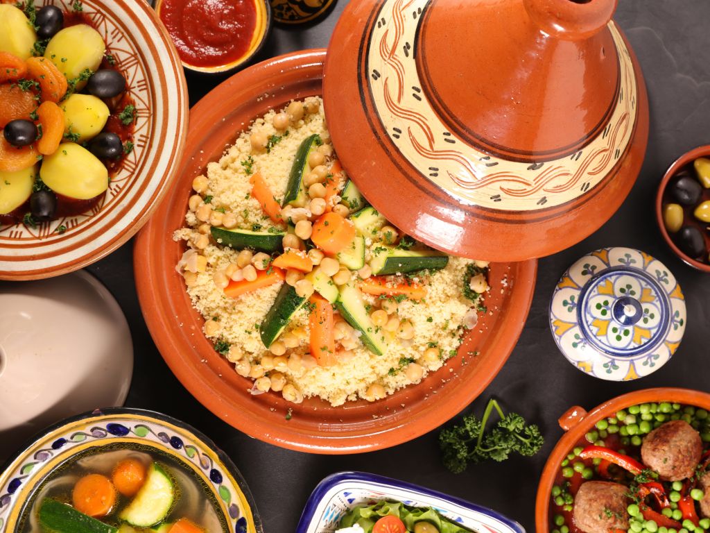 Tavola ricca di piatti tradizionali tunisini, tra cui tajine e couscous.