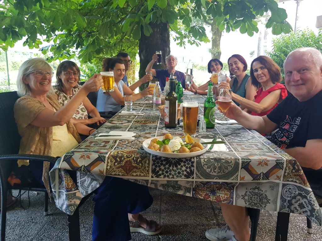 Gruppo di persone che brindano a una tavola all’aperto in un villaggio delle Alpi Giulie, Slovenia.