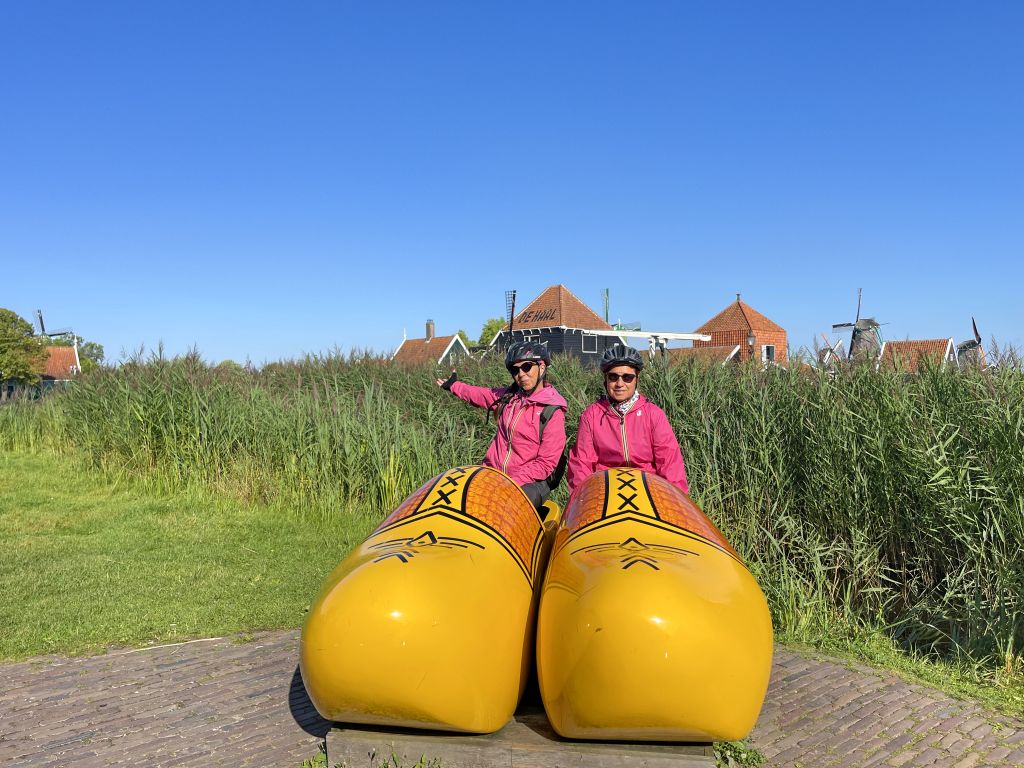 Tourist taking a picture on large yellow clogs in a Dutch field, Netherlands