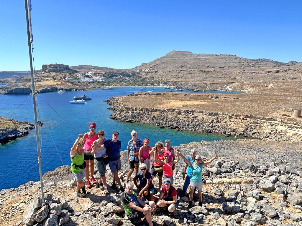 Gruppo di trekking vicino alla Baia di San Paolo, Lindos, con vista sul mare e sul paesaggio collinare, Rodi, Grecia. Viaggiare in gruppo.