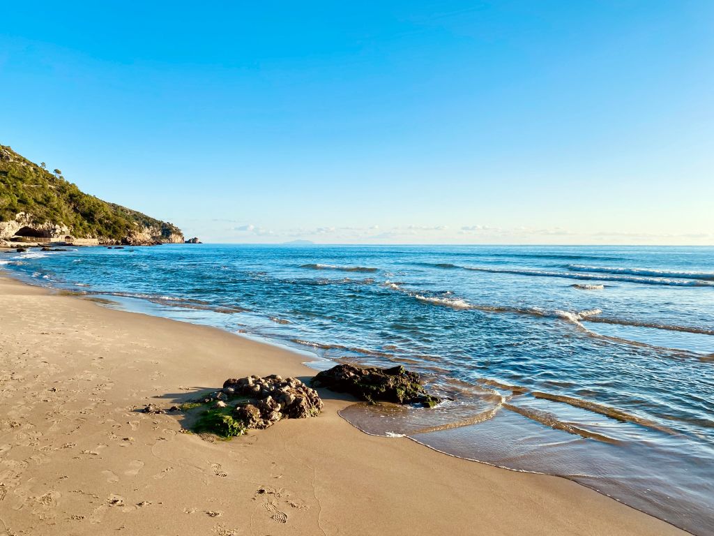 Spiaggia sabbiosa con mare azzurro e vegetazione costiera a Sperlonga, Lazio.