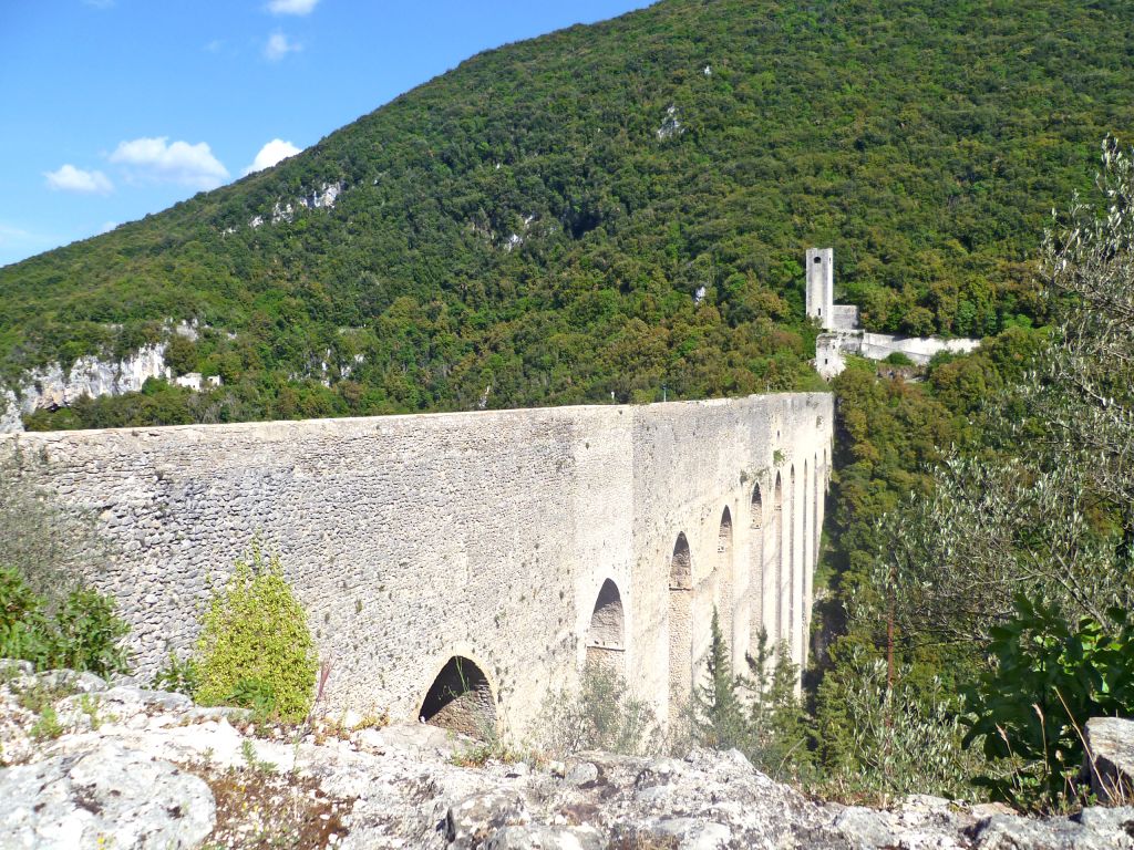 Vista panoramica del Ponte delle Torri a Spoleto con vegetazione e colline verdi circostanti.