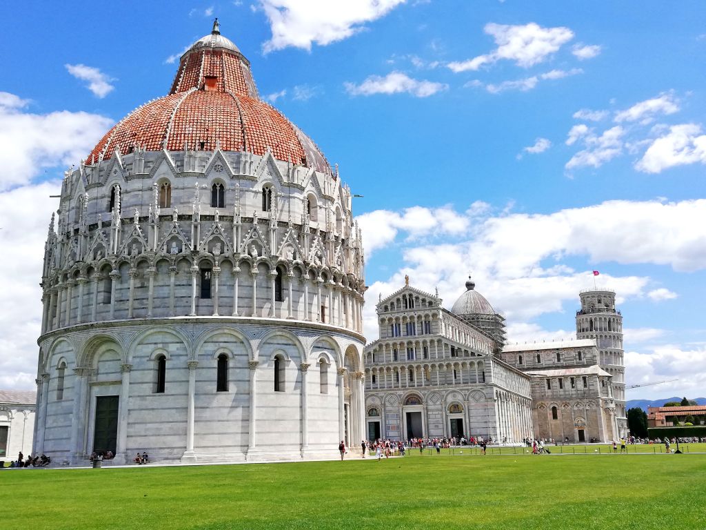 La Cupola del Battistero di Pisa con il Duomo e il Campo dei Miracoli sullo sfondo in una giornata di sole, Toscana.
