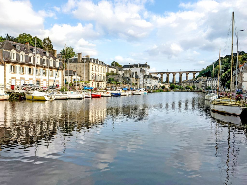 Centro storico di Morlaix con case a graticcio, riflessi nel fiume e il caratteristico viadotto in pietra sullo sfondo