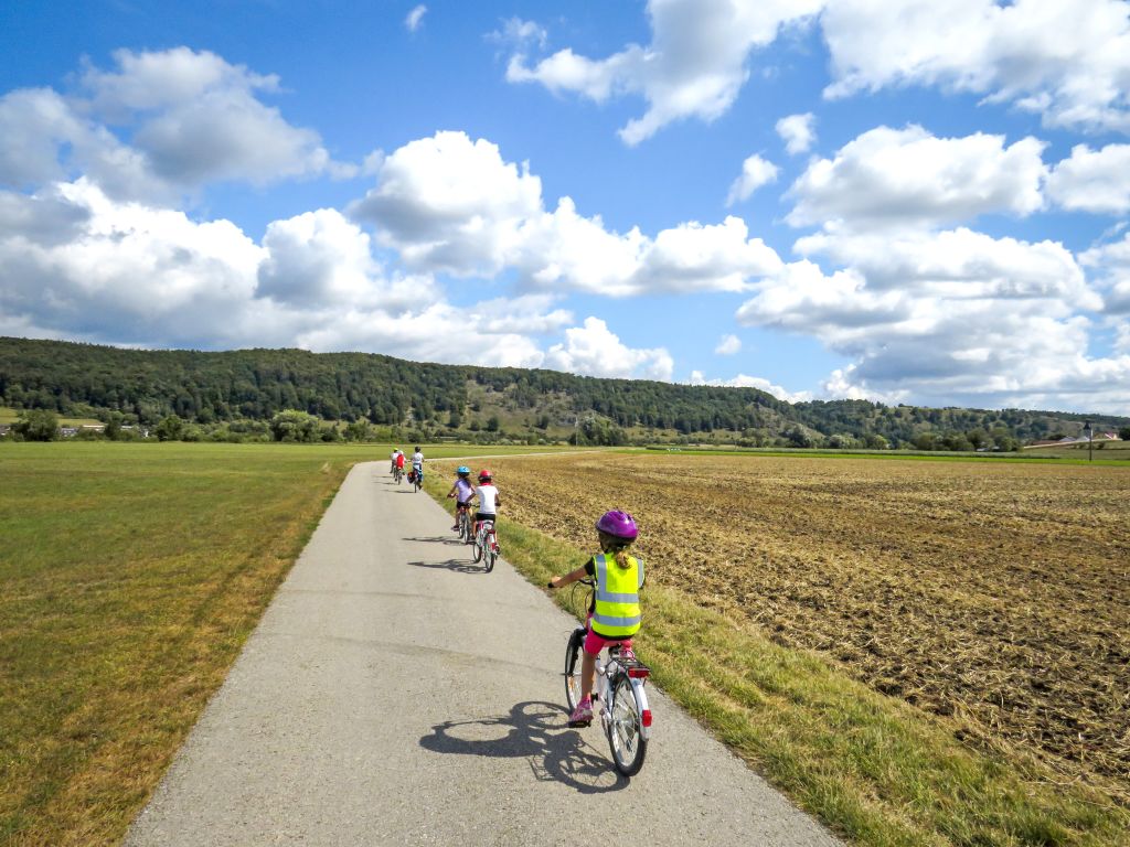 Famiglia che pedala su pista ciclabile panoramica tra i campi in Germania.