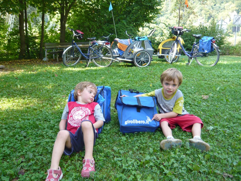 Due bambini seduti sull’erba vicino alle bici durante una pausa in un parco della Germania.