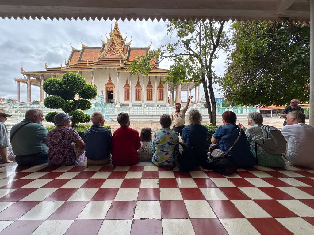 Gruppo di viaggiatori seduto sulla terrazza a scacchi davanti alla Pagoda d’Argento del Palazzo Reale di Phnom Penh, Cambogia