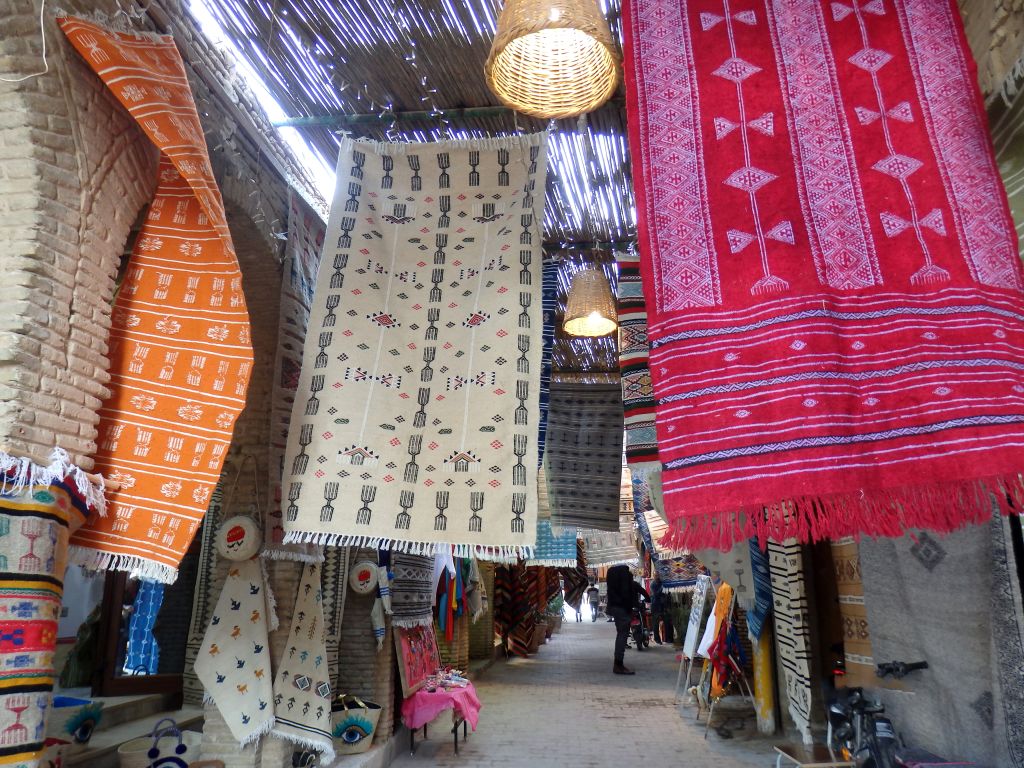Tappeti berberi colorati appesi tra le botteghe del souk nella Medina di Kairouan, Tunisia
