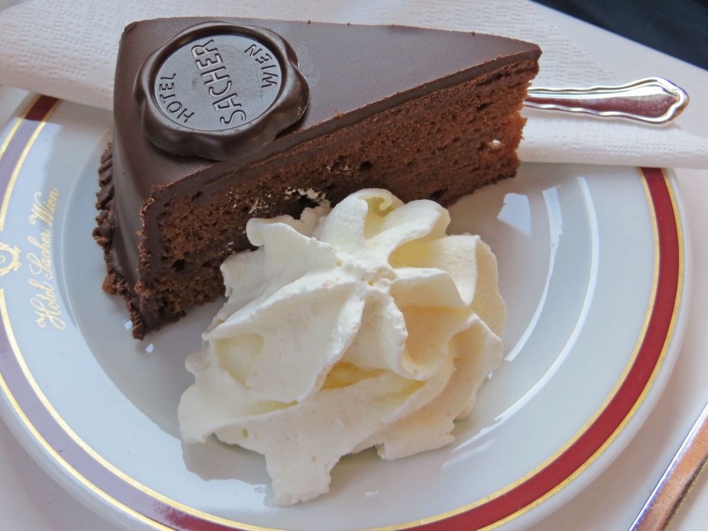 Original Viennese Sachertorte slice with whipped cream served in a traditional café, Vienna – Austria food experience