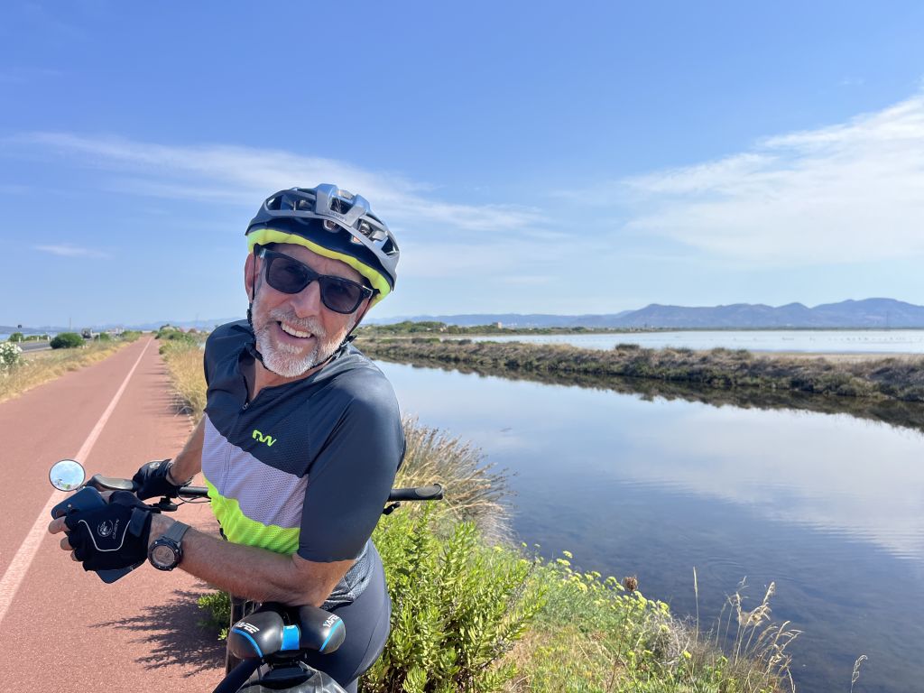 Cicloturista Girolibero con casco lungo un percorso costiero in Sardegna.