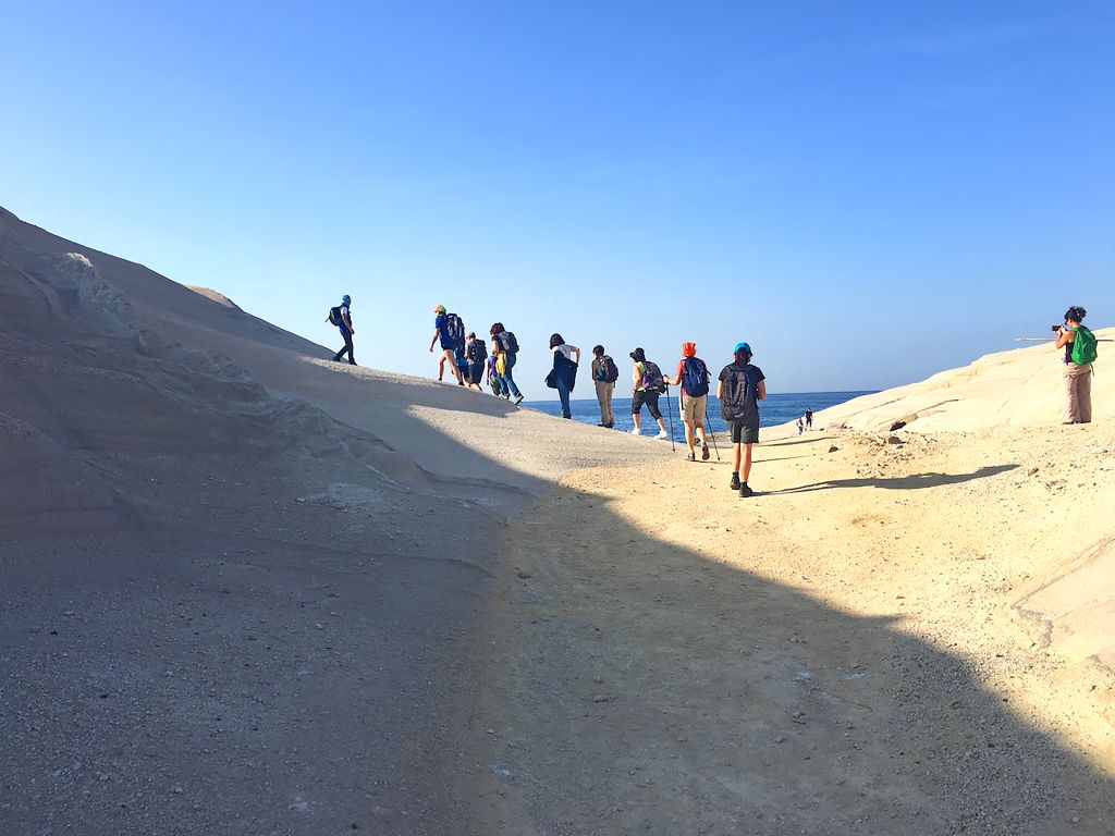 Escursionisti lungo il sentiero panoramico in Grecia illuminato dal sole pomeridiano.