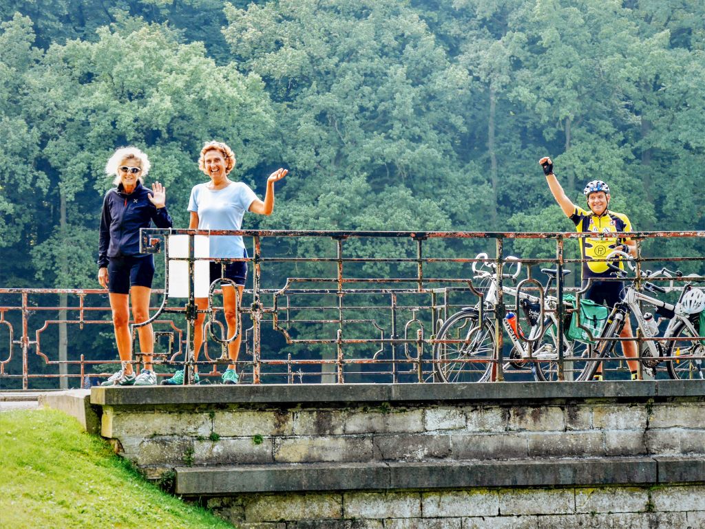 Ciclisti fermi su un ponte in un area verde lungo la ciclabile, tour in bici delle Fiandre