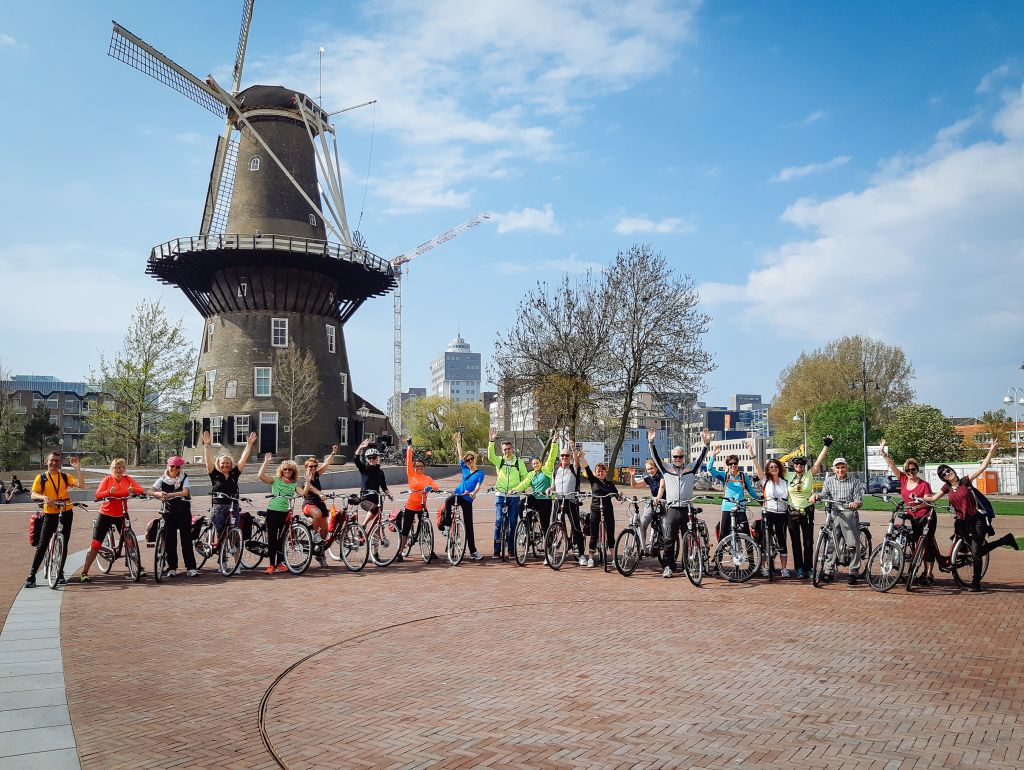 Group of tourists cycling near a blooming tulip field, Netherlands.