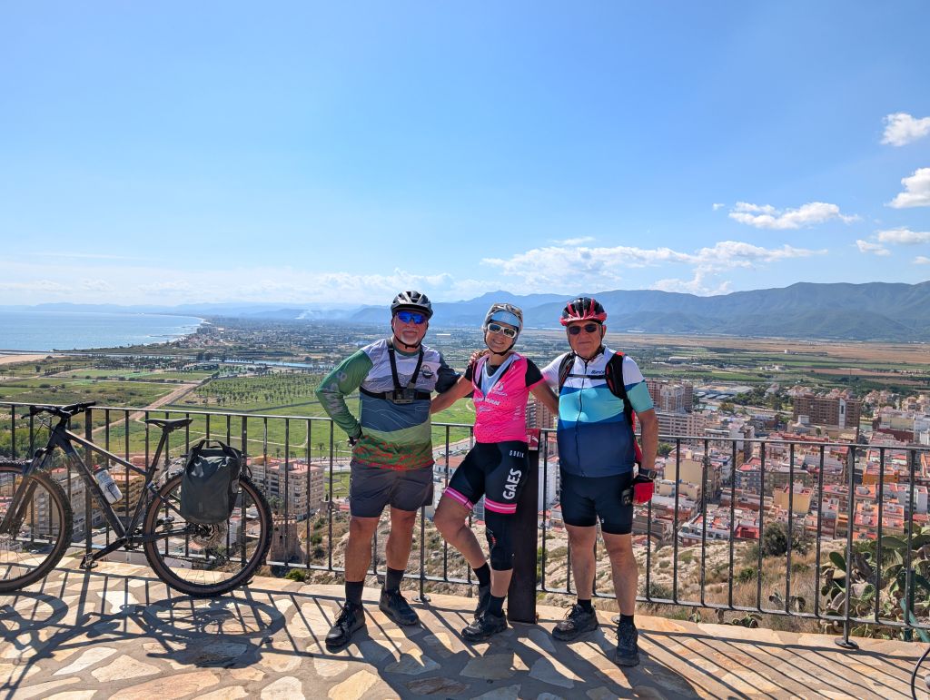 Gruppo di ciclisti in pausa panoramica su un belvedere collinare della Spagna mediterranea.