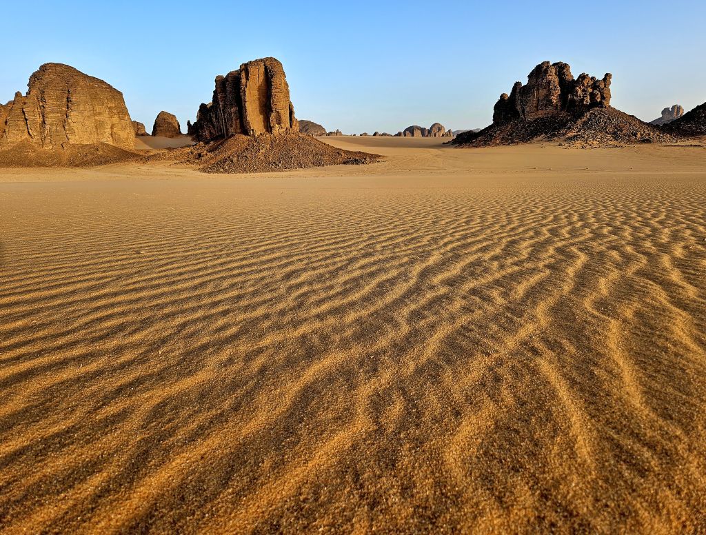 Deserto del Sahara, Algeria - Panorami sabbiosi e dune nel Sahara, con formazioni rocciose sullo sfondo.