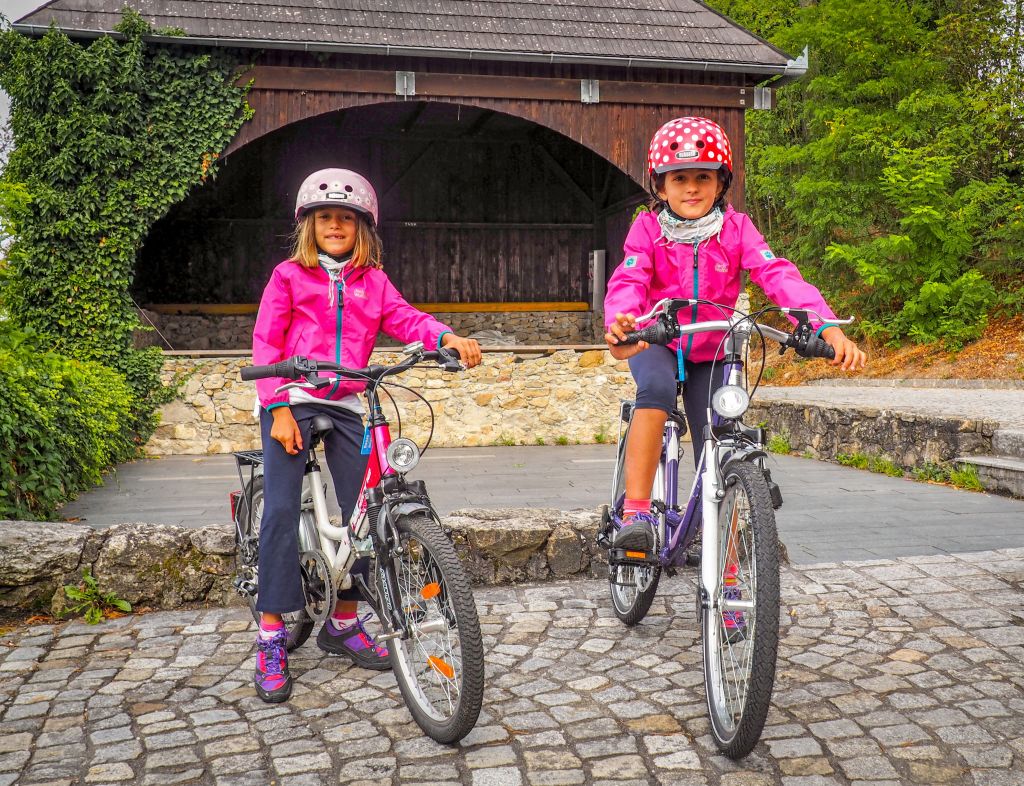 Bambine in bici con caschetto e giacca rosa, paesino austriaco lungo la ciclabile del Danubio tra Linz e Vienna