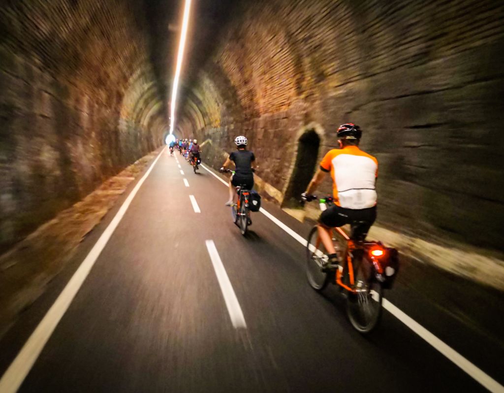 Biciclette che percorrono un tunnel ciclabile illuminato lungo la Ciclovia dell'Alpe Adria, Austria.
