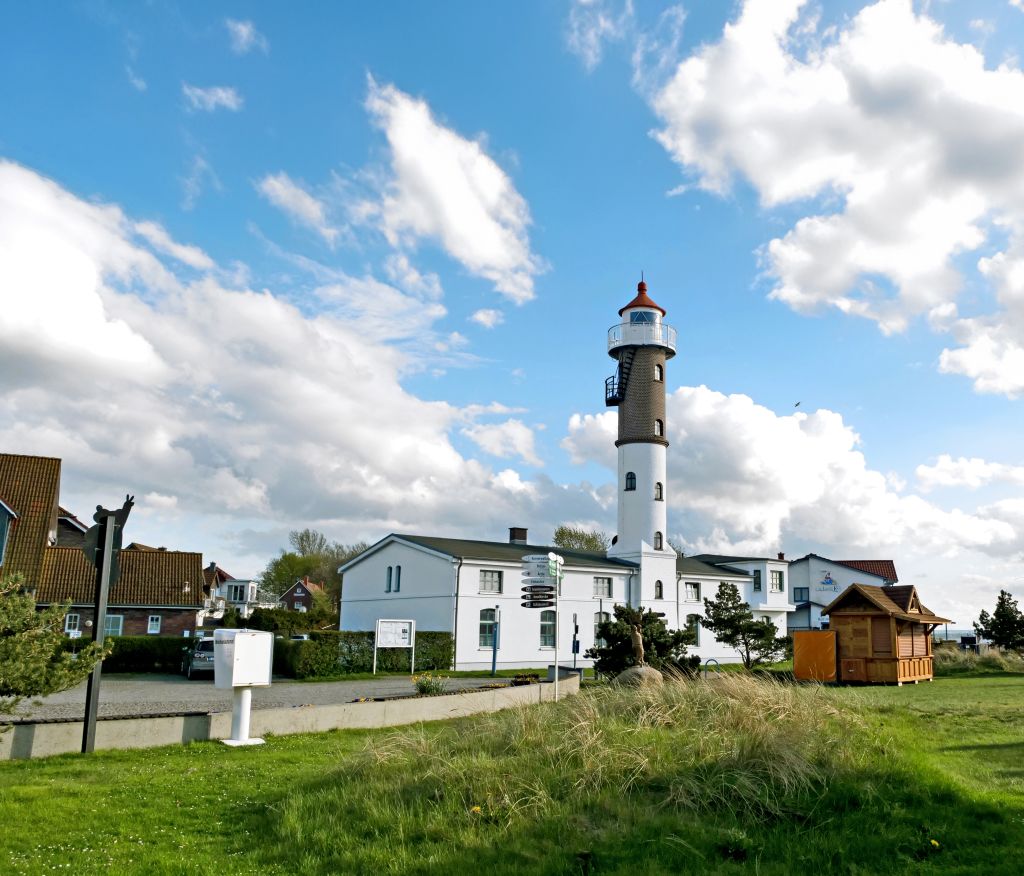 Piccolo faro su edificio bianco circondato dal verde vicino alla costa baltica.