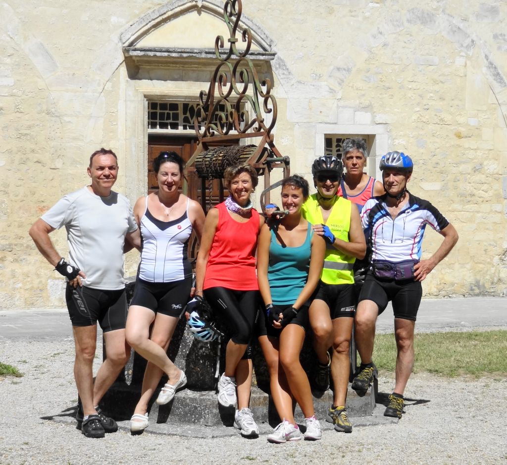 Gruppo di ciclisti in posa davanti a una fontana storica in un villaggio del Cognac, Francia