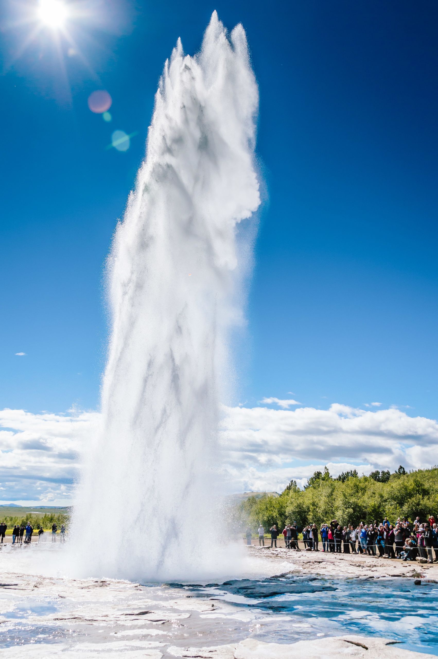 Il geyser Strokkur che erutta un potente getto d'acqua sotto il cielo azzurro, zona geotermica di Geysir, Islanda.