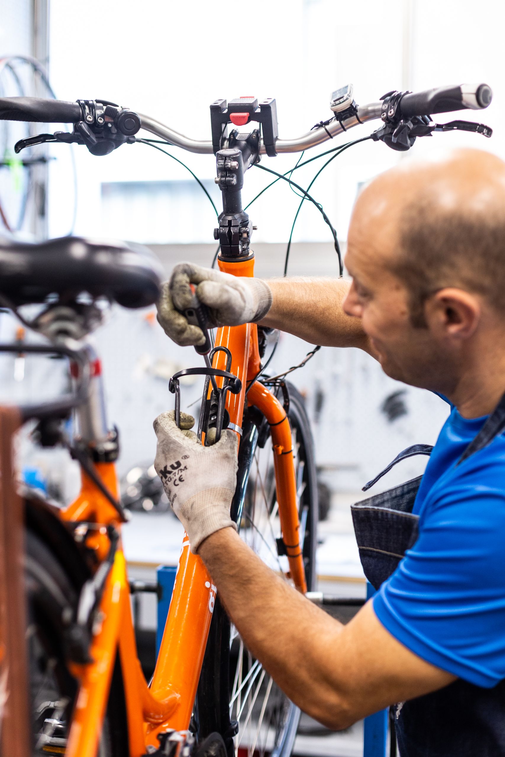 Mechaniker repariert ein orangefarbenes Fahrrad in der Girolibero-Werkstatt