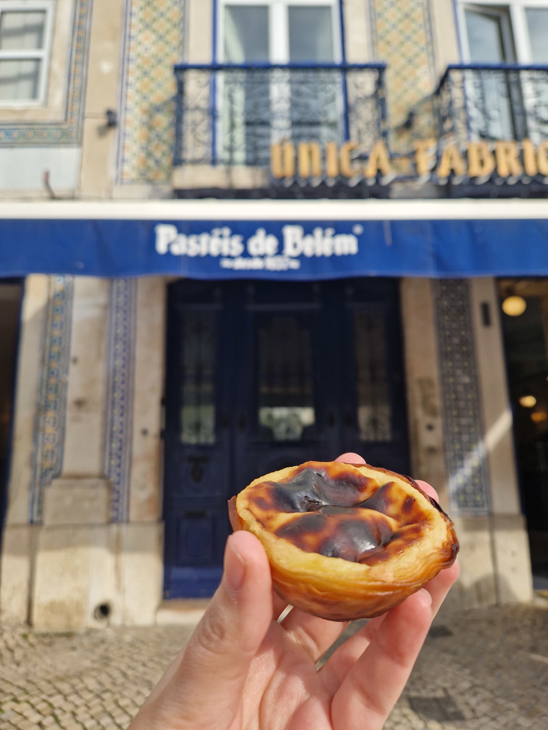 Pastéis de nata davanti alla storica pasticceria Pastéis de Belém a Lisbona, Portogallo.