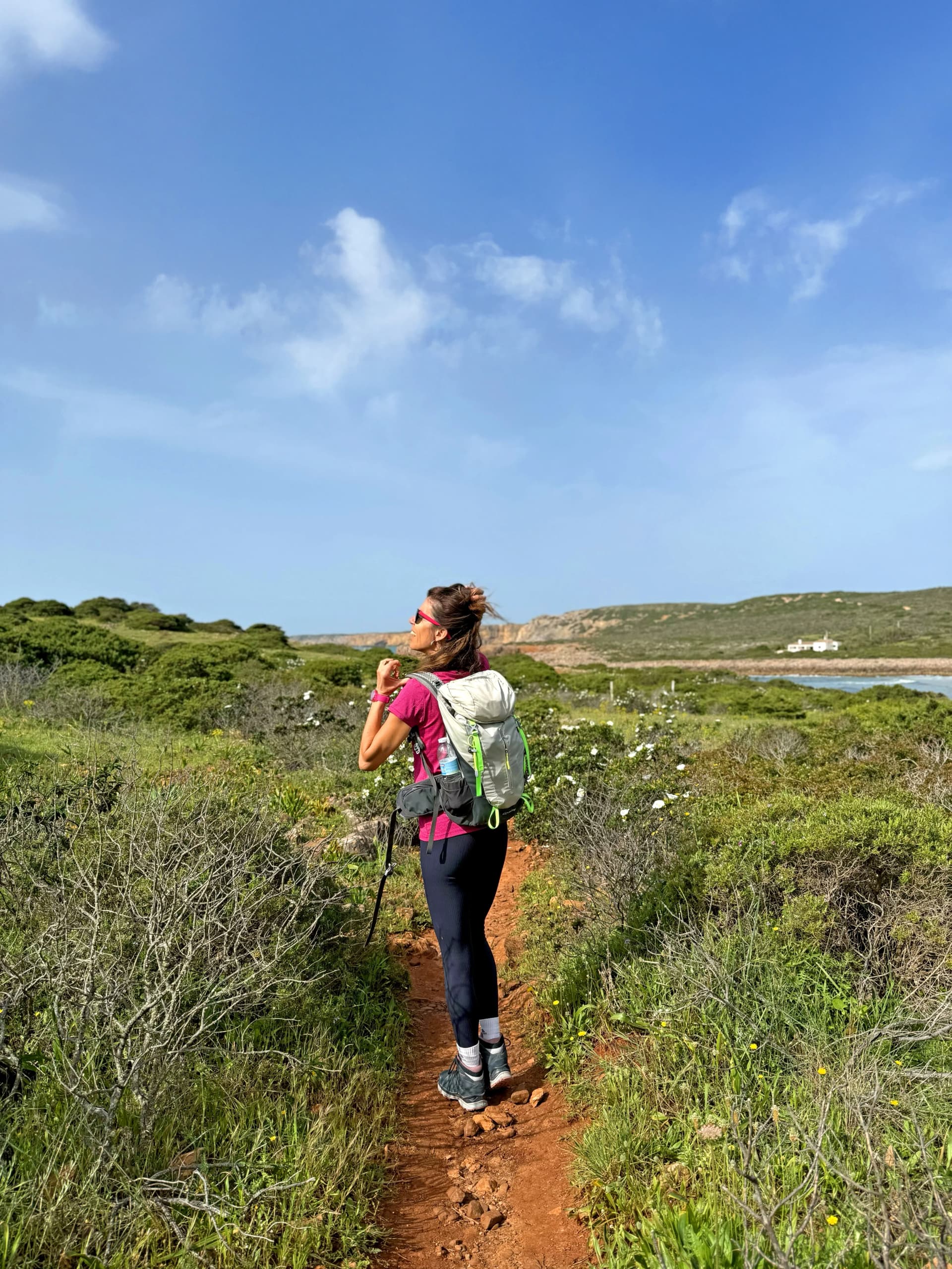 Escursionista sul Sentiero dei Pescatori (Rota Vicentina) tra erica e cisti in fiore vicino Carrapateira, Algarve occidentale.