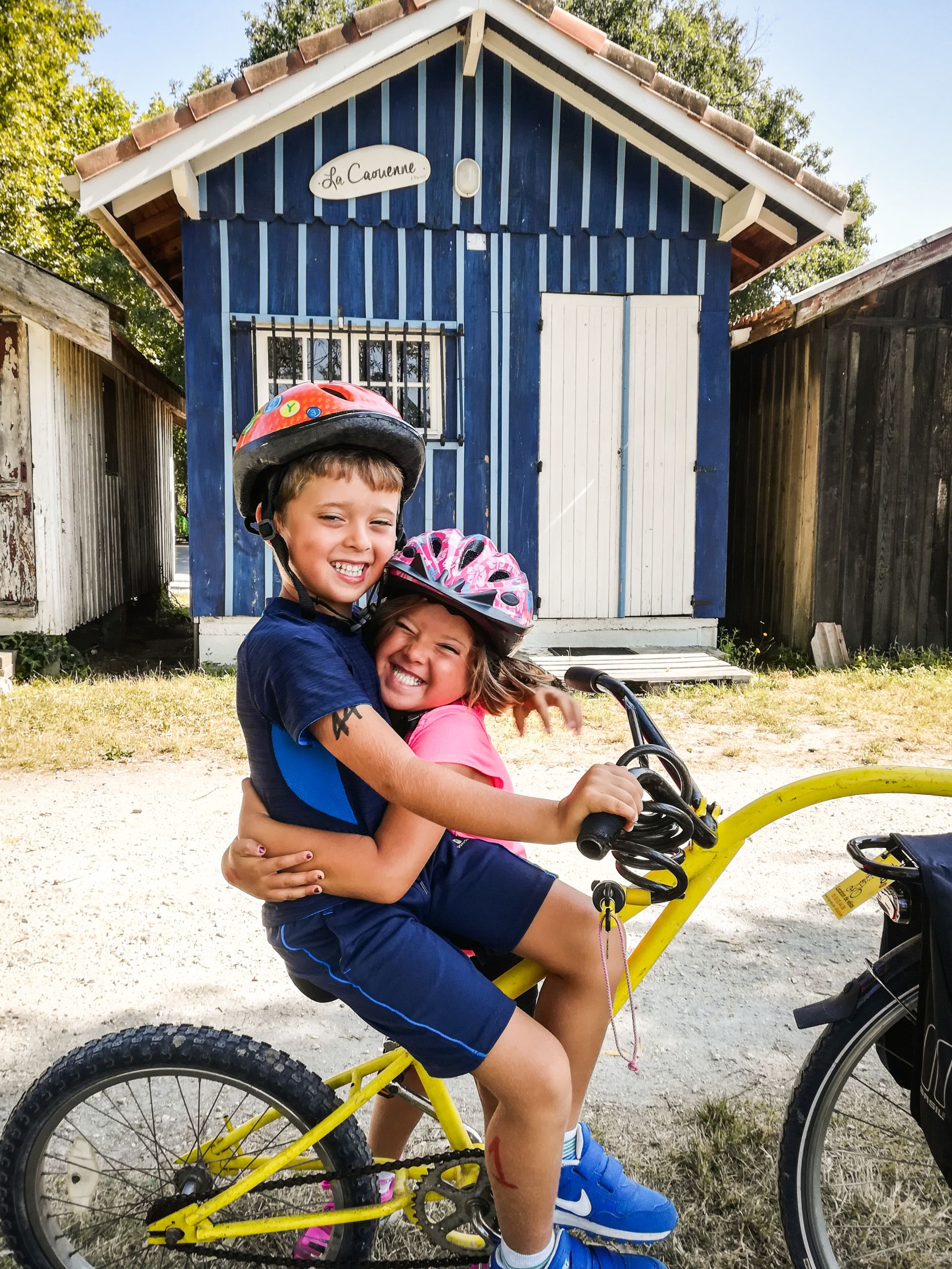 Bambini si abbracciano felici su una bicicletta, Francia in bici in famiglia