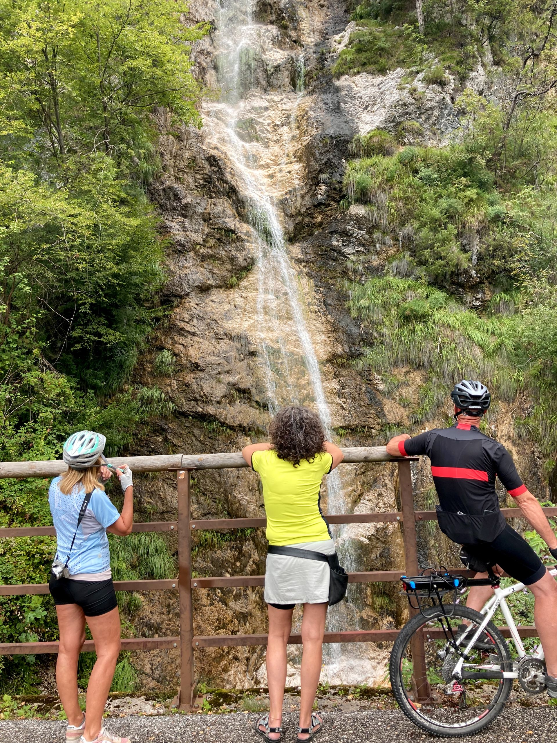 Ciclisti che osservano una cascata lungo la ciclovia dell'Alpe Adria