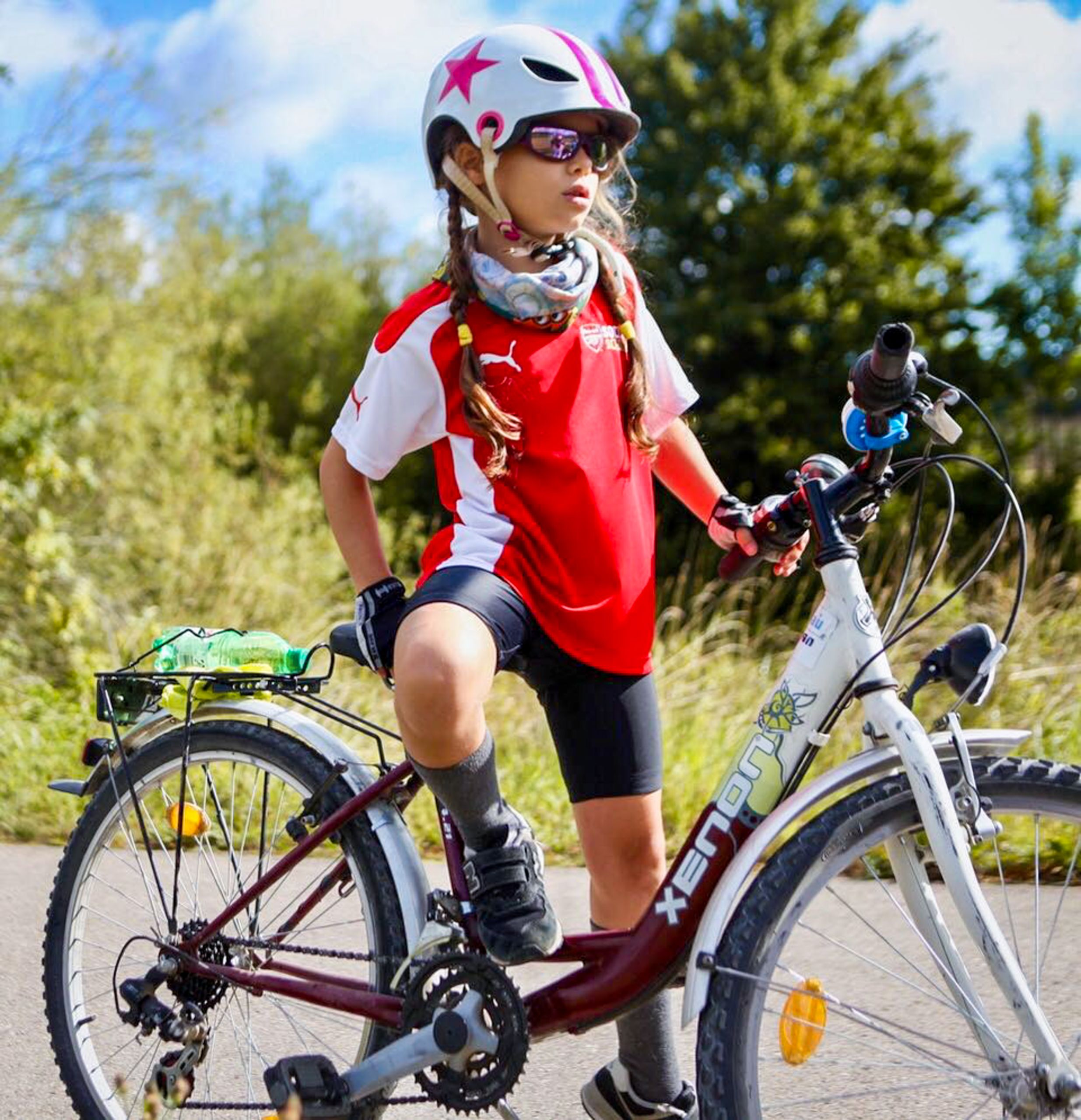 Bambina su bicicletta con casco e maglietta rossa, viaggio in bici in famiglia con Girolibero.