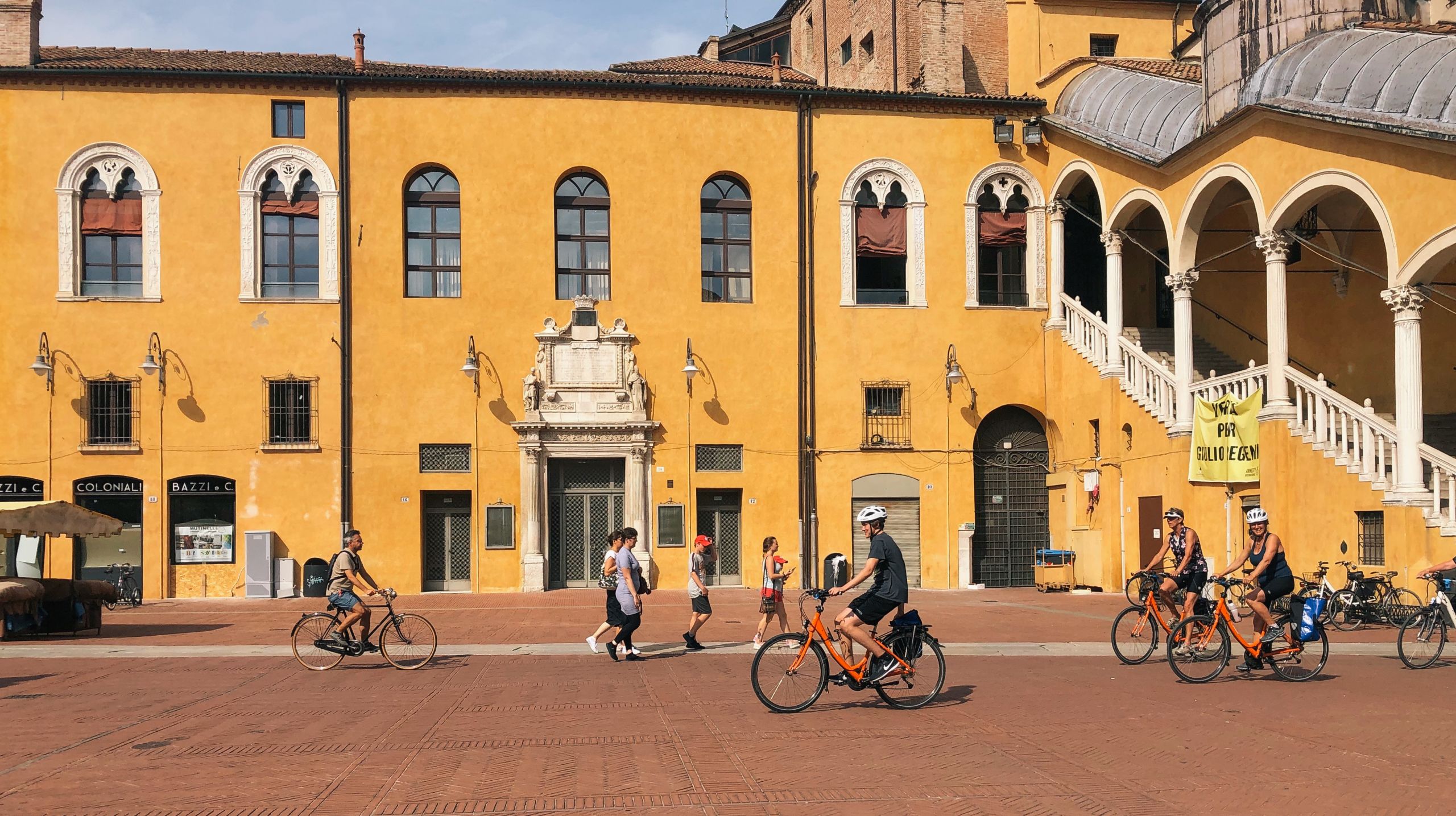 Cicloturisti attraversano una piazza storica, Mantova.