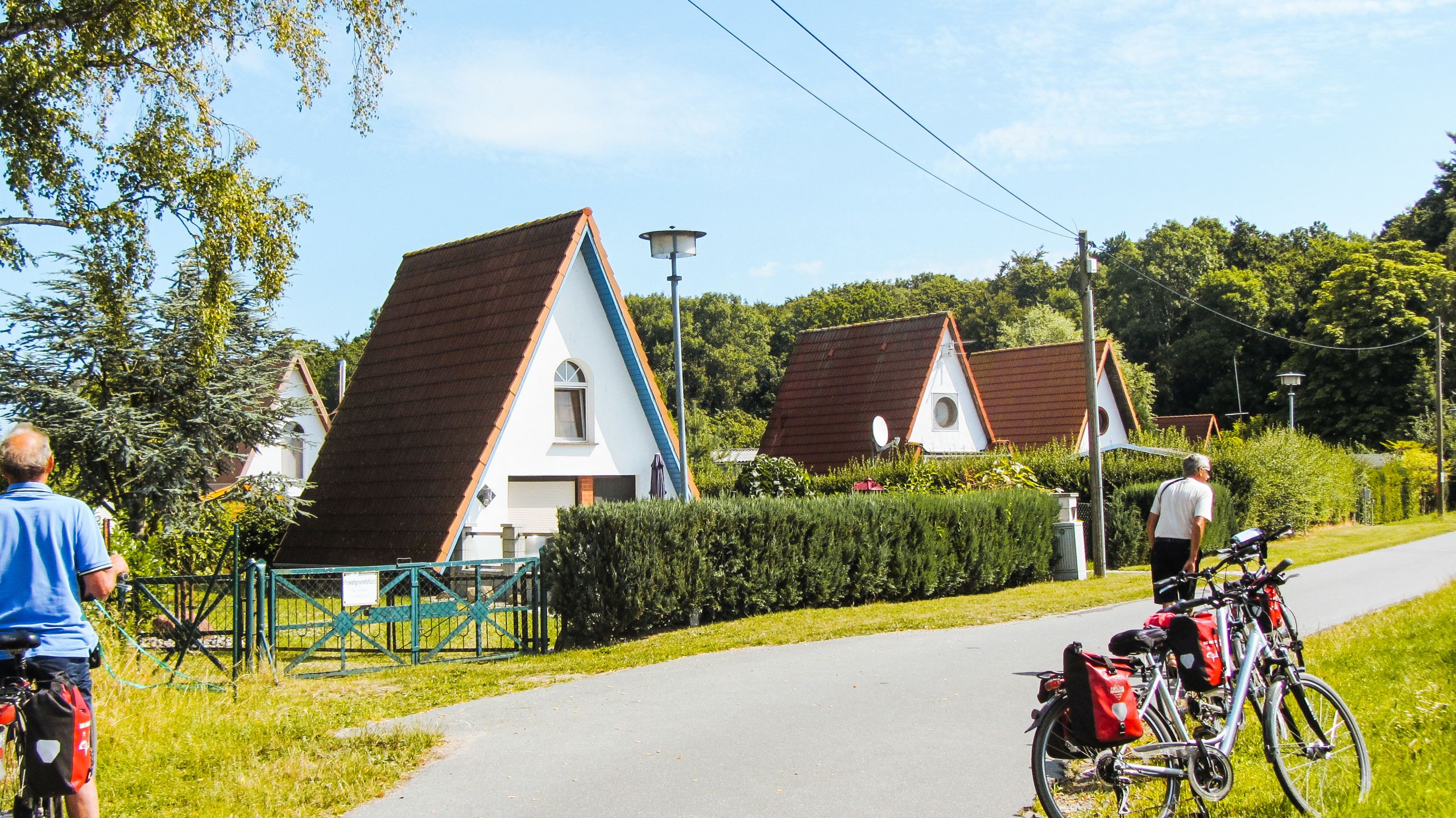 Cicloturisti, paesaggio verde, case a triangolo marroni e bianche, vacanza all'aria aperta, Mar Baltico, Germania