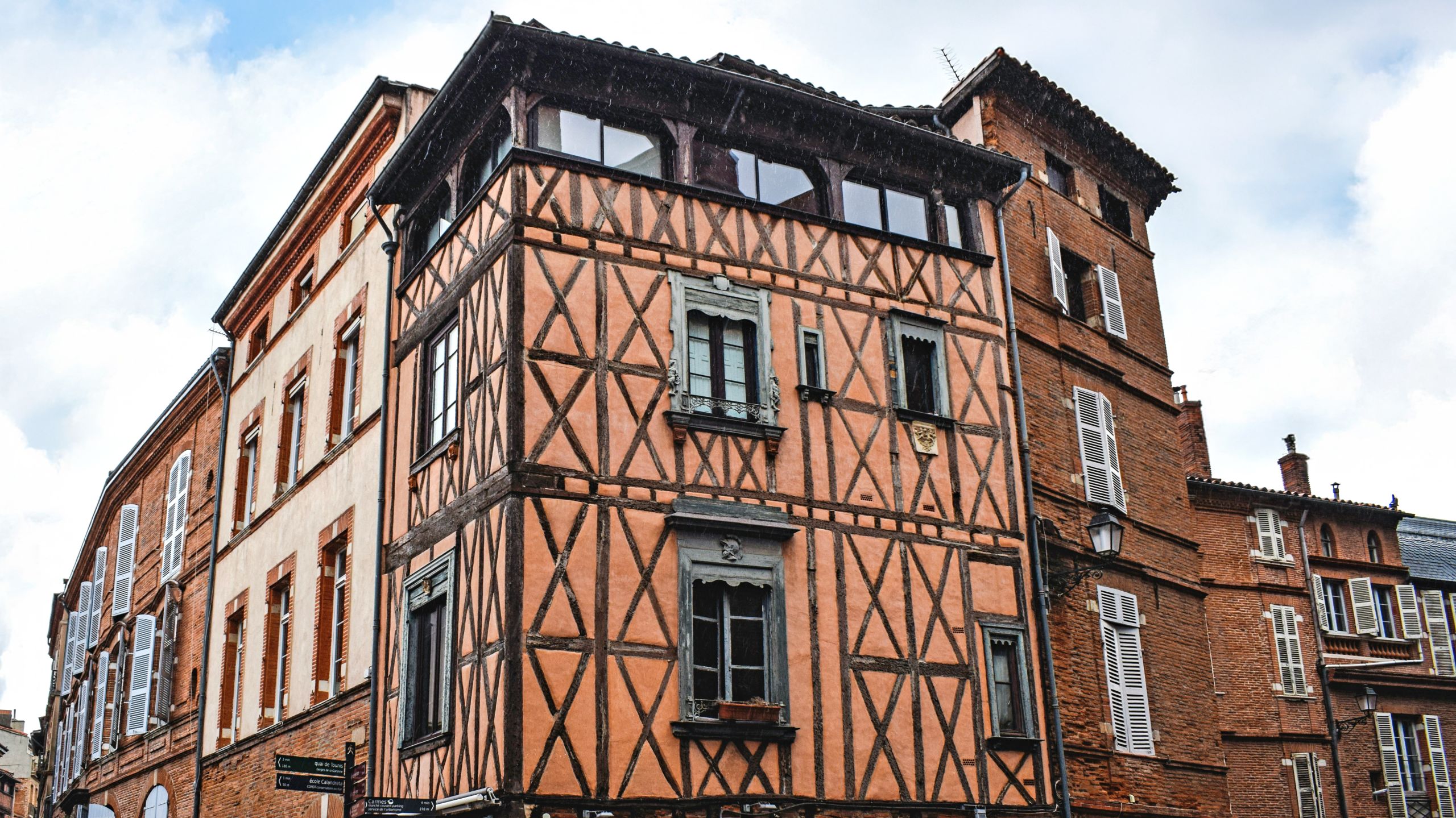 Palazzo a graticcio nel centro storico di Tolosa, Francia, con cielo sereno.