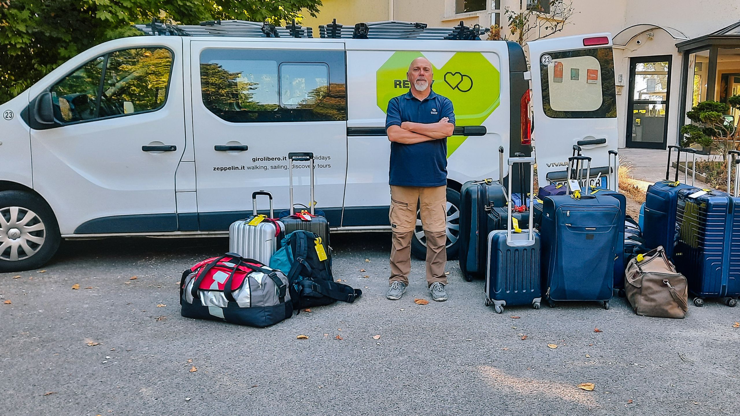Girolibero-branded van parked with luggage and a cyclist ready for a tour.
