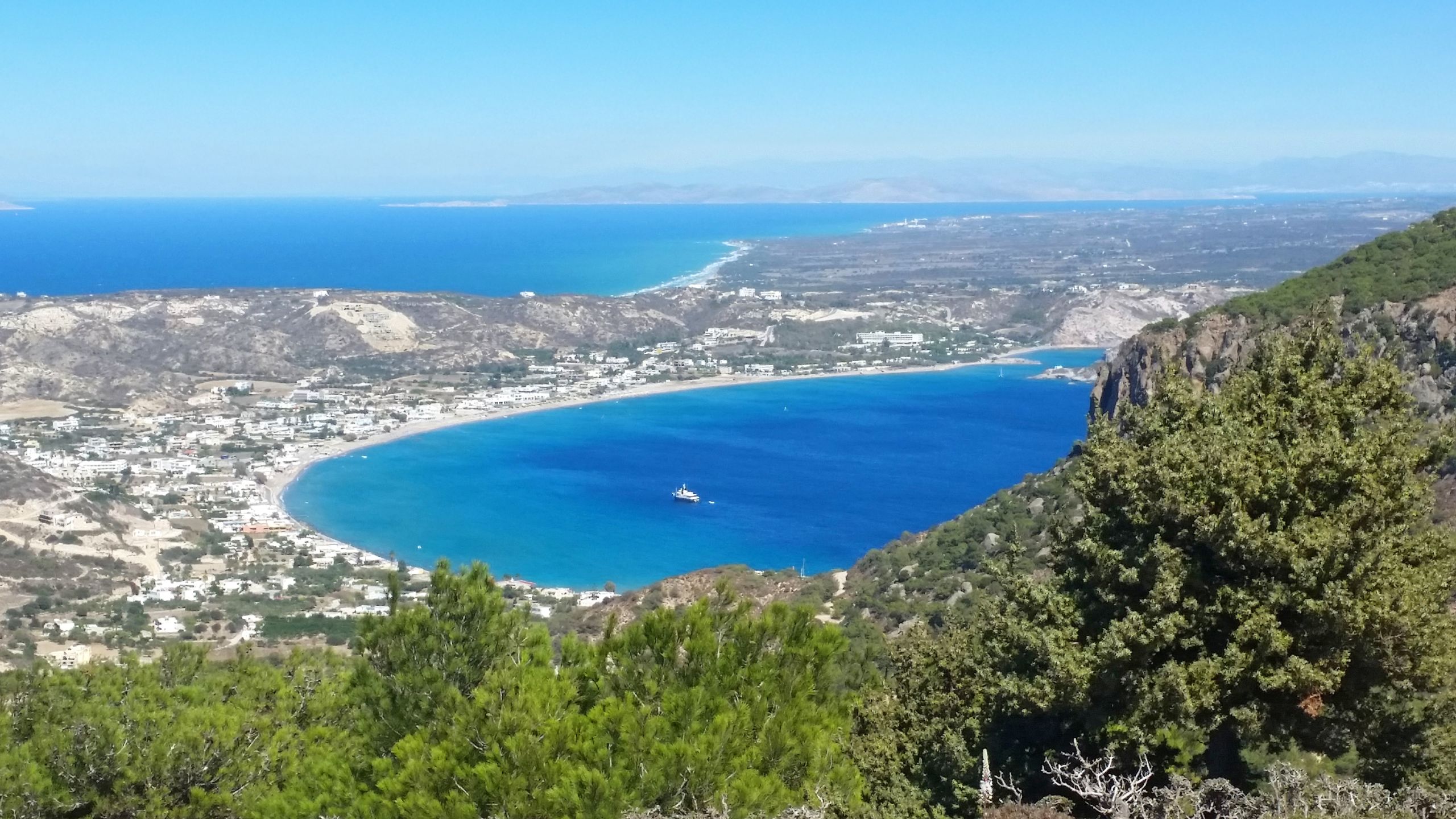 Panoramica sulla Baia di Kefalos con mare cristallino e vegetazione.