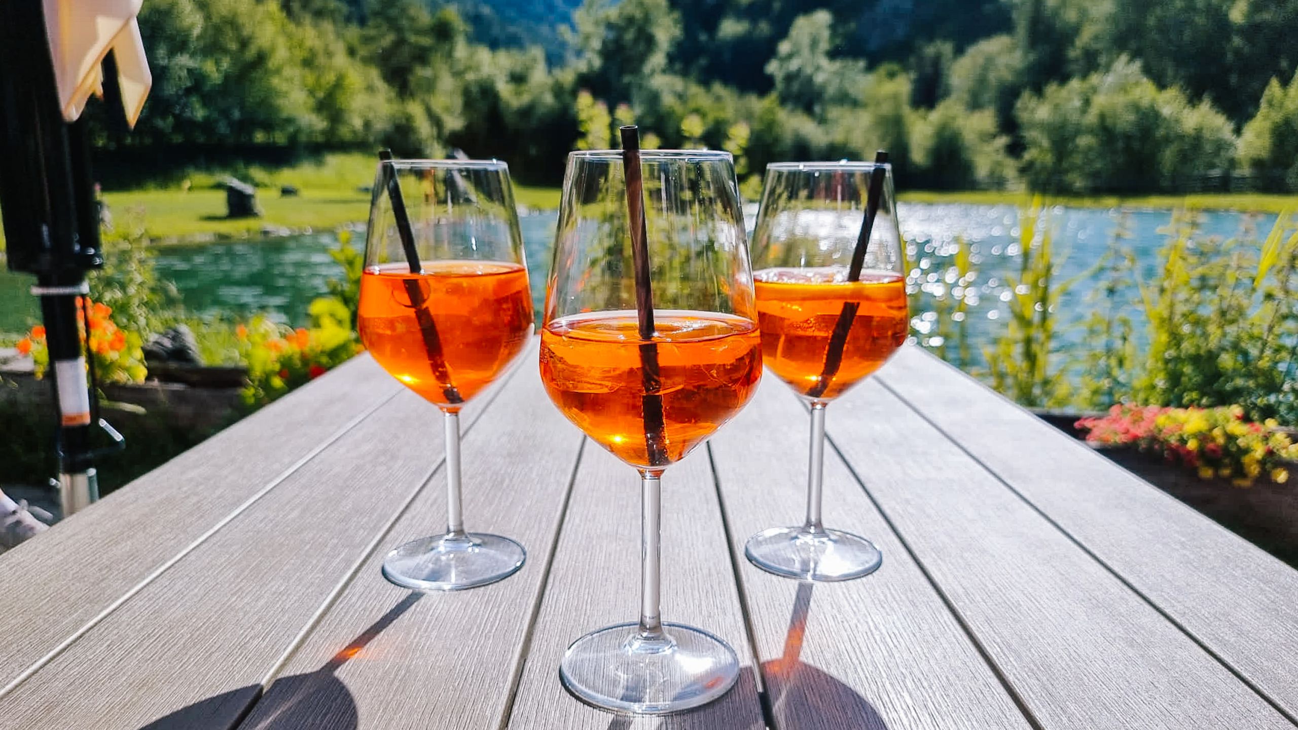 Glasses of spritz on a table with a view of the vineyards in South Tyrol, Italy.