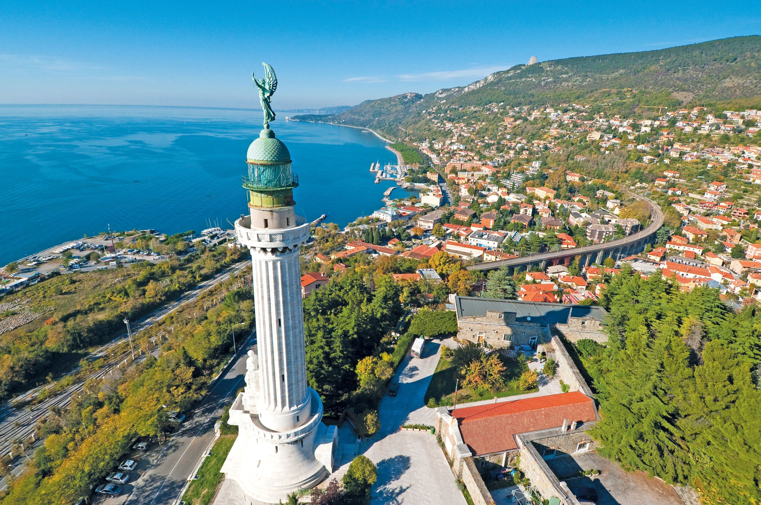 Faro della Vittoria, paesaggio verde, case con tetti rossi, porto, golfo di Trieste, vacanza in bici, Friuli Venezia Giulia