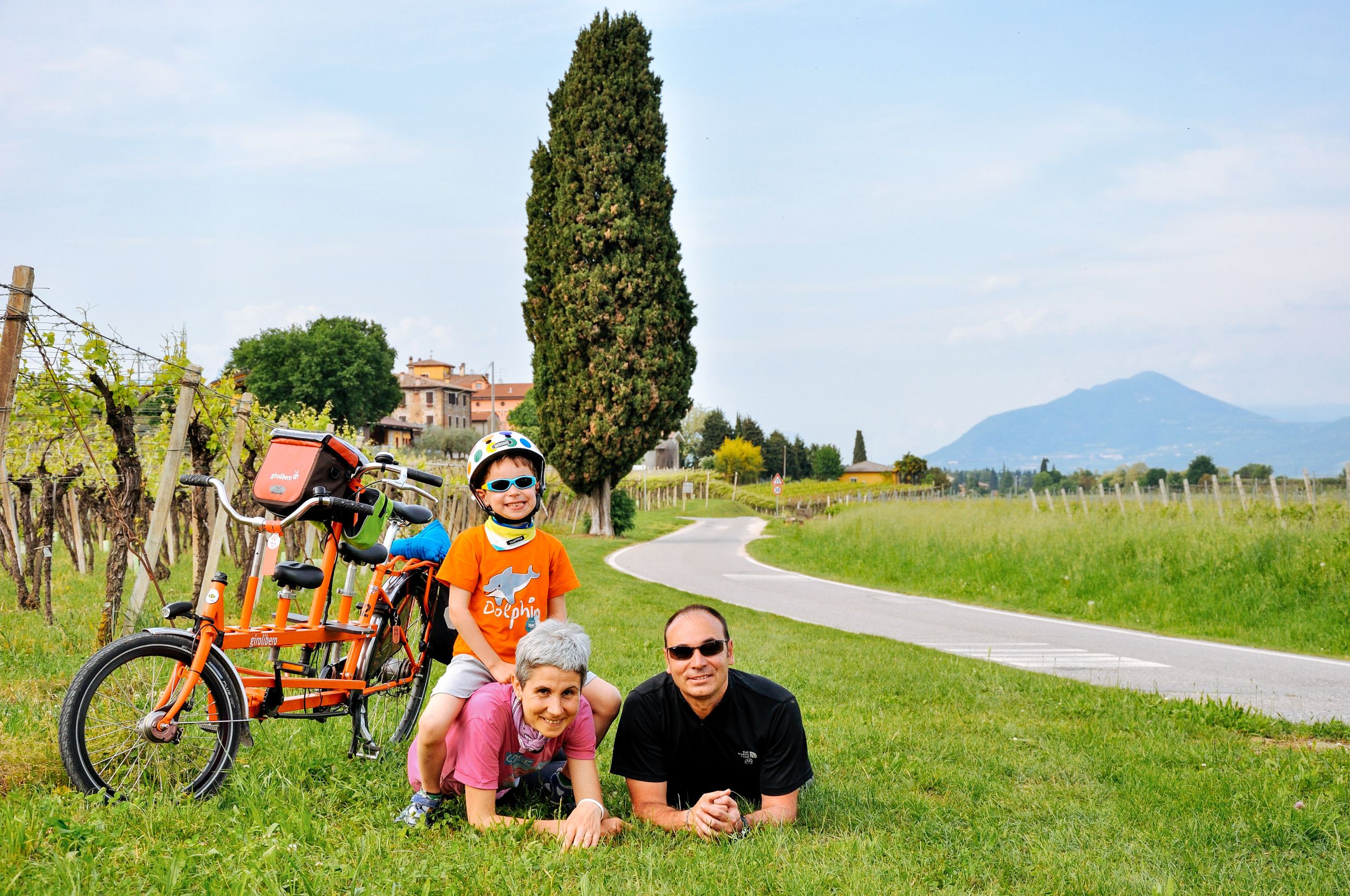 famiglia in posa con bici Girolibero e paesaggio naturale sullo sfondo