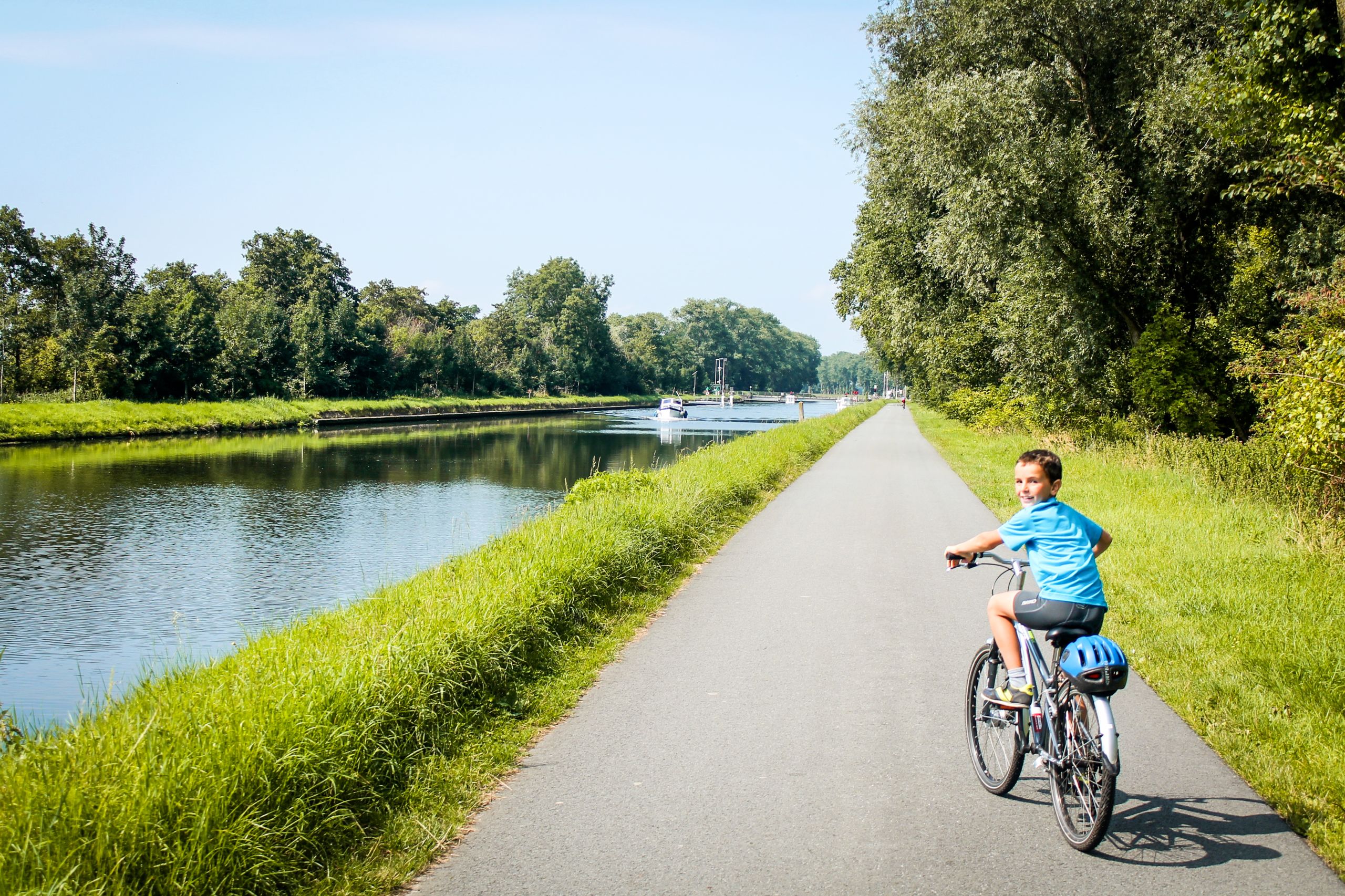 Bambino in bici, paesaggio verde pieno di alberi, fiume, vacanza all'aria aperta, Fiandre, Belgio