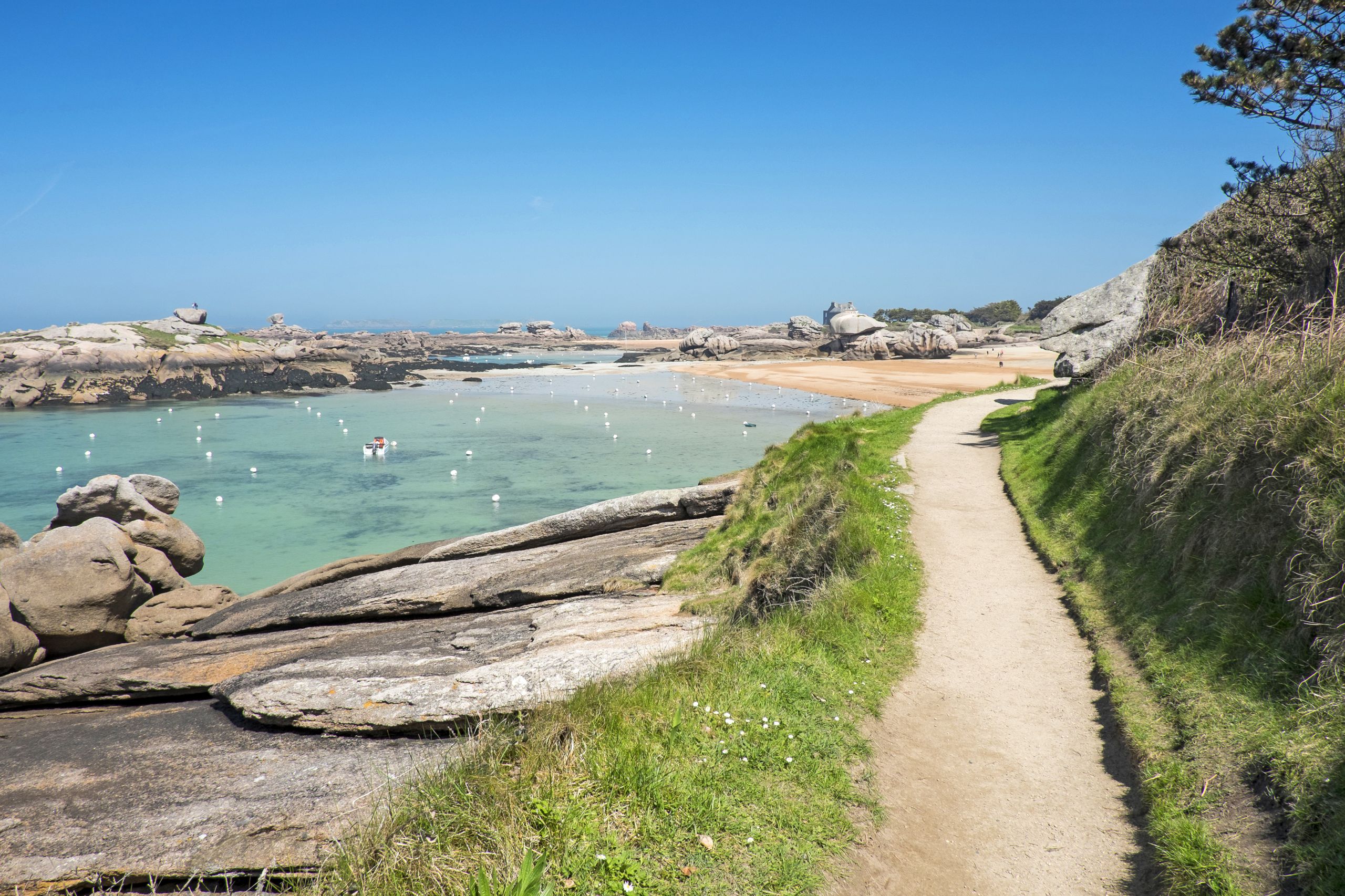 Sentiero costiero con rocce granitiche e mare turchese in Bretagna.